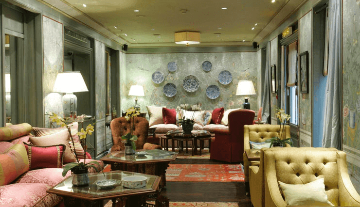 Hôtel Daniel à Paris, entre épopée fabuleuse en et route de la soie, croisé d'influences orientales. Un 4 étoiles exotique affilié à Relais & Châteaux. A dix mille lieues des enseignes aseptisées. Hôtel Daniel, à Paris. A priori, un lieu de rendez-vous pour amoureux. A deux pas des Champs-Elysées, rue Frédéric Bastiat, le Daniel attire par son côté bonbonnière aux touches pastels et extrême-orientales dans la tradition des chinoiseries rococo. A priori, seulement. Pour l'homme d'affaires, le Daniel se distingue des autres 4 étoiles parisiens, incitant au repos mérité avant ou après une négociation. D'emblée, on s'y sent bien dans cet immeuble haussmannien, comme rassuré. On n'y entre pas, on s'y laisse guider. Tout, dans la décoration, invite au voyage. Un boudoir orientaliste façon XVIIIe d’autant plus réconfortant lorsqu’on arrive l’après-midi et que l’on croise des clients venus tester les goûters qui font la renommée de l’endroit : un tea-time revisité mêlant mini-sandwiches, scones, clotted cream, cake et autres pâtisseries sans oublier une fort belle carte de thés. Un voyage, donc. A moins que ce ne soit, déjà, une forme d'abandon, un lâcher-prise. Et si vous venez prendre possession de votre clé, prenez le temps de vous poser dans le salon. Vous imprégner. Tara Salam, la décoratrice britannique, a délibérément choisi le style français du XVIII siècle dans l'esprit des chinoiseries. Disons-le tout net : ça plait... ou pas. Mais si on aime, on adore les papiers peints en fleurs, les tapis Khotan. Dans la ville empressée, vous êtes ici dans une oasis; il manque juste le bruit de l'eau qui ruisselle, le chant des oiseaux. Alors, poussez la curiosité jusqu'au bar et au restaurant : un mur de vitrines abrite une somptueuse collection de verrerie d'art; des papillons nacrés dessinent des arabesques sous un lampadaire en cuivre échappé du Lotus bleu. Fatigués des hôtels aseptisés, des salons uniformes et des chambres impersonnelles ? Laissez-vous aller. Laissez-vous transporter. Le Daniel ce pourrait être le point de départ d'une expédition, le temps du séjour, même si ce n'est qu'une nuit. La toile de Jouy au mur des chambres est une invitation : ici Kipling raconte une chasse à dos d'éléphant, là des musiciens mongols font résonner leur luth, là encore une demoiselle se laisse conter fleurette... Il flotte comme un air de maison de famille au Daniel. Vite, on vous on vous reconnait. Le savoir-recevoir, ici, a tout son sens. Le site s'y prête : 19 chambres et 7 suites, pas plus. Préférez, si possible, les chambres des cinquième et sixième étages, avec terrasse. Dans chaque chambre, une atmosphère particulière avec des couleurs, des tissus et des meubles différents : boites chinoises, bureaux et tables de nuit incrustés de nacre, coffres en bois précieux... Tout est dans le détail. Les placards, par exemple ont des allures de meuble de famille avec leurs portes vitrées, grillagées, recouvertes de petits rideaux. Exotisme jusqu'au bout. Les salles de bains sont habillées de zelliges du Maroc et de marbre italien aux couleurs claires -certaines, même, ont des fenêtres avec lumière du jour tamisée par des voilages de lin de Russie. Un écrin dans l'écrin. Encore une fois, on aime ou pas. Mais si on aime, on adore. Hôtel Daniel 8 rue Frédéric Bastiat (Champs-Elysées) 75008 Paris 0033 1 42 56 17 00 www.hoteldanielparis.com